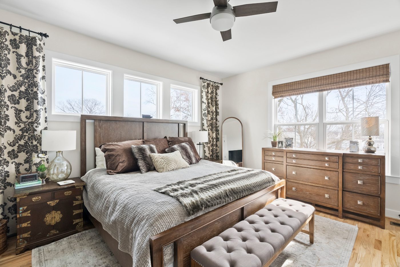 Neatly staged bedroom with neutral bedding and open light